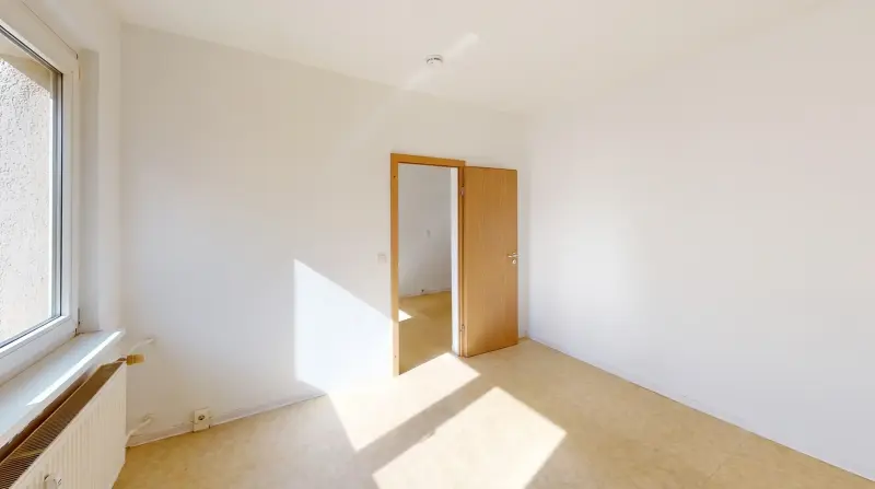 Helles Schlafzimmer mit Fenster und offener Tür zum Wohnbereich